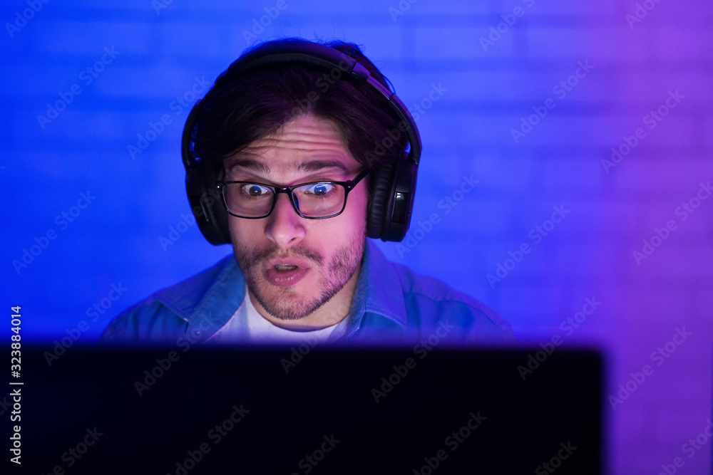 Poster shocked gamer having problem playing computer game at home, low-light