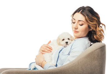 woman holding Havanese puppy and sitting on armchair isolated on white