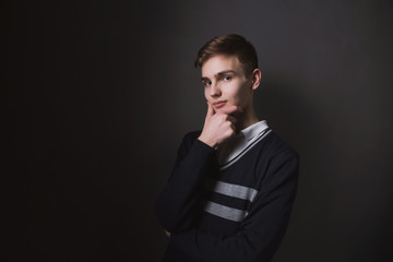 Lifestyle photo of a young brown-haired man on a light background, a beautiful young guy in a shirt and sweater