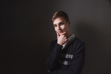 Obraz premium Lifestyle photo of a young brown-haired man on a light background, a beautiful young guy in a shirt and sweater