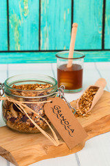 Drahtbügelglas mit gesundem Granola Müsli auf einem Holzbrett mit Getreideschaufel und...