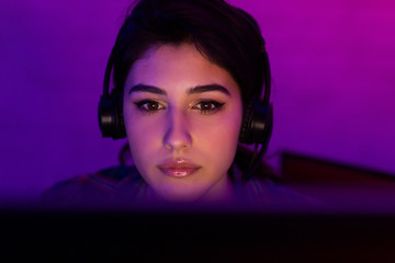 Millennial Girl Gamer Playing Videogame On PC Indoor At Night