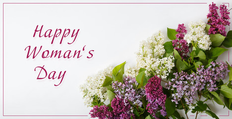 Greeting Card for celebrating Woman's Day. Bouquet of white and purple lilac on white background. Top view. Text Happy Womans Day. Spring blossom mood. Copy space for your text. Post card for woman