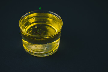 Green soap falling on olive oil in a low glass. Isolated on a black background.Copy space