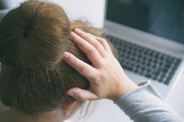 Fototapeta premium Stressed businesswoman touching head with hands and looking at the laptop screen