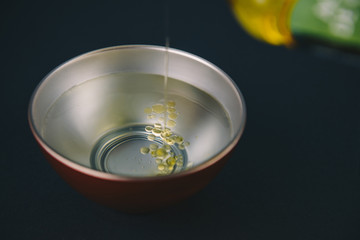 Olive oil falling on water, with drops of oil on the water, in a red and silver bowl with oil bottle reference.Abstract concept,can't be mixed.Copy space