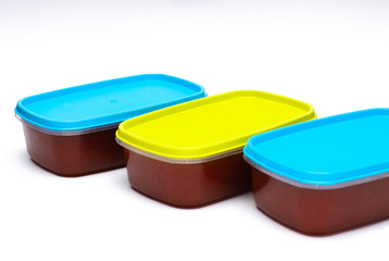 3 tupperwares of preserved quince in a white background