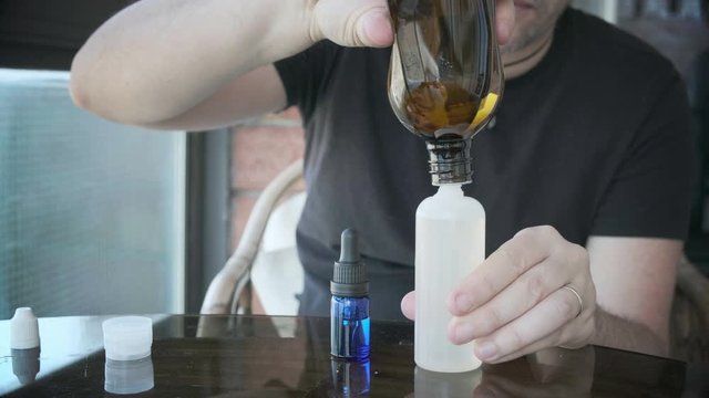 man is mixing liquid or e-liquid in bottle for e-cig or electronic cigarettes