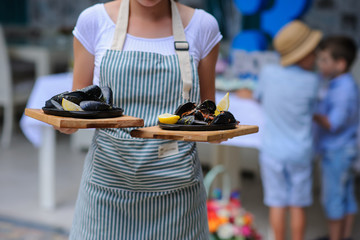 Waiter holding two plates with tasty mussels