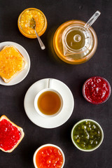 Obraz na płótnie Canvas Tea party with jam. Toast, teapot, cup on black background