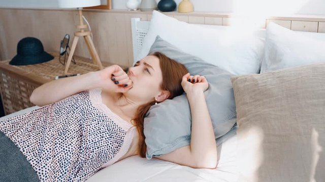 Girl in apartment sleep cozy bed irritated by noise behind wall cannot sleep nervous. Woman cover head pillow not hear screams and noise neighbors. Cute girl waking up in cozy bed sunny morning