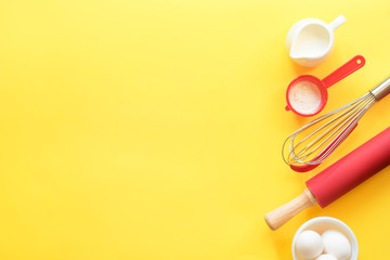 Kitchen devices for baking and ingredients on a bright yellow background. Top view, copy space....