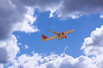 An airline plane flying in a blue sky inside big white clouds. Image with copy space.