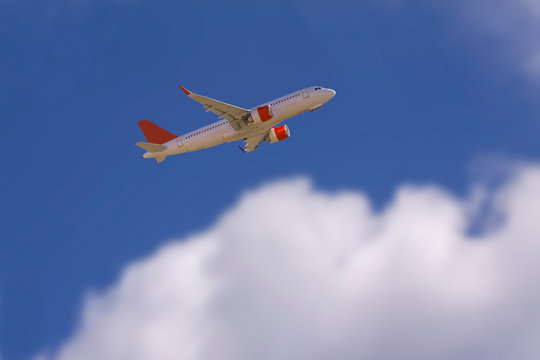 An airline plane in the blue sky flying above big white blurred clouds. Image with copy space.