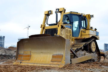 Obraz na płótnie Canvas Bulldozer during of large construction jobs at building site. Crawler tractor dozer for earth-moving. Land clearing, grading, pool excavation, utility trenching and foundation digging.