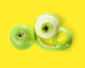 Two green apples with peeled skin isolated on yellow background. Top view