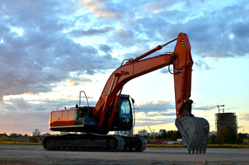 Large tracked excavator on a construction site background of the  awesome sunset. Road repair,...