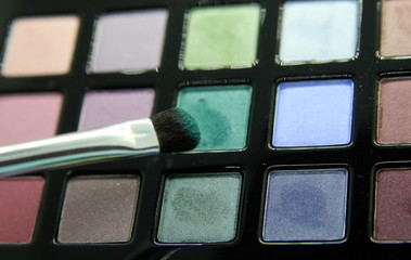 a set of eye shadow in various colors and a brush