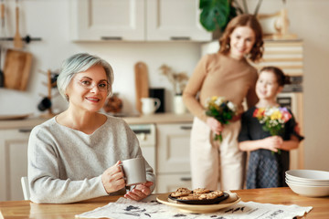 mother's day! three generations of  family mother, grandmother and daughter congratulate on the holiday, give flowers