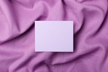 Top view of blank cardboard on the purple linen fabric.Empty card for sale text, prices or design