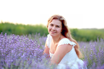 Fototapeta na wymiar a young woman in a white sundress walks in a lavender field, enjoying the aroma and relaxing at the weekend