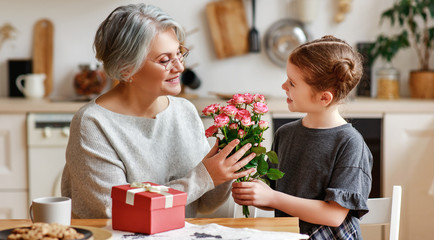 happy family. child granddaughter congratulates her grandmother and gives her flowers and a gift.