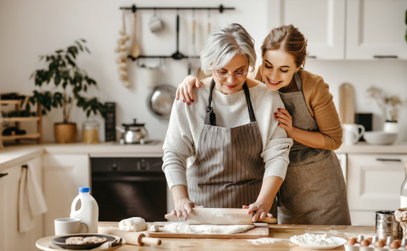 happy family grandmother  old mother mother-in-law and daughter-in-law daughter cook in kitchen, knead dough, bake cookies.
