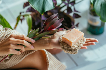 Woman hands holding natural organic solid green soap bar made with olive oil on blue background....
