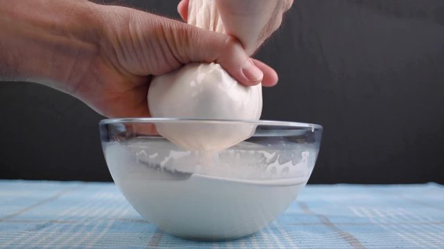 Hands of squeezing the almond milk bag or cheese cloth. The process of making almond milk. Sideways movement.