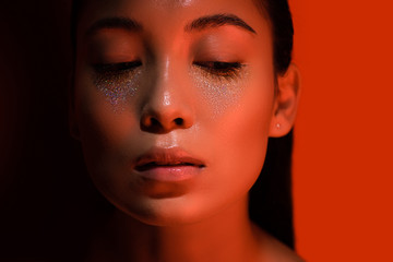 beautiful asian girl with silver sparkles on face on red and black
