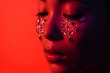 beautiful asian girl with rhinestones on face isolated on red