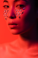 beautiful naked asian girl with rhinestones on face isolated on red