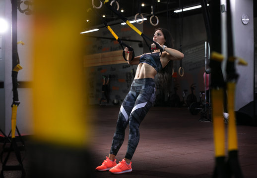 Sport backgrounds. Powerful attractive muscular woman fitness trainer do battle workout with ropes at the gym.	