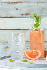 Grapefruit juice with mint in glasses on the table. Refreshing summer cocktail.