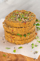 Raw veggie burger with lentils, vegetables and thyme leaves on kitchen countertop.