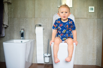 Happy baby boy learning to use toilet for defecate and urinate