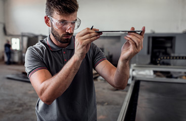Young engineer setup plasma cutter for work in metalwork workshop.