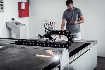 Young engineer setup plasma cutter for work in metalwork workshop.