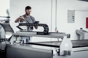 Young engineer setup plasma cutter for work in metalwork workshop.