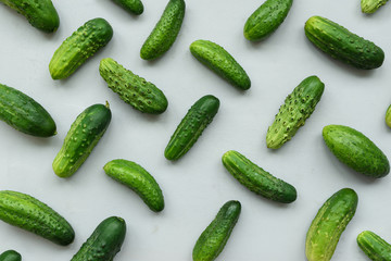 Green cucumbers pattern on gray wooden background. Harvest concept. Top view. Flat lay.