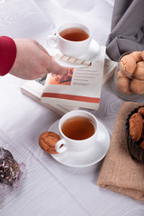 Sweet snacks, cup of tea and chocolate and book on light background
