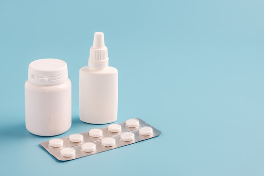 Two White Plastic Medicine Bottles For Pills Without Labels And Pill Packaging On Blue Background. Copy Space For Text