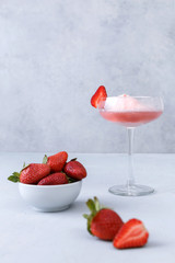Pink champagne  glass with strawberry ice cream on a gray background. The concept of delicious drinks. Copy space