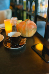 Cup of coffee with cookie on the table in a cozy cafe.