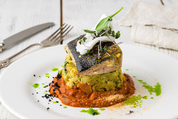One piece of baked salmon grilled pepper lemon and salt on a brown plate with lettuce leaves. wood background