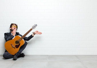 young musician man sitting on the floor with a guitar