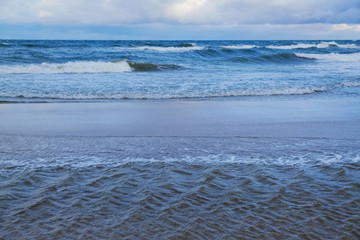Sea shore with waves flooding the sand and creating interesting patterns. Baltic Sea, Dziwnowek, Poland