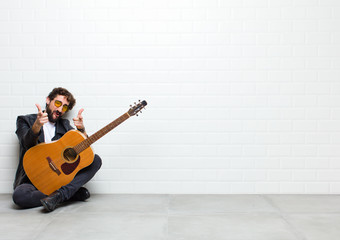 young musician man sitting on the floor with a guitar