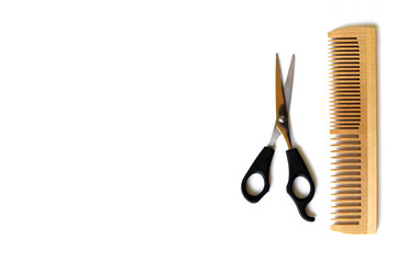 Wooden comb and scissors for a haircut isolated on a white background.