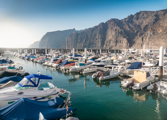 Fototapeta na wymiar Beautiful image of harbor with moored motorboats and yacht at Los Gigantes, Tenerife island